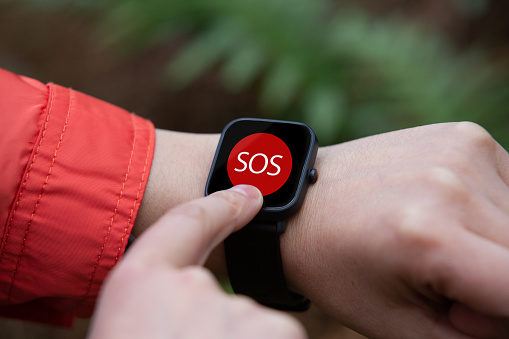 hands of a woman calling for help from the emergency service through the smart watch