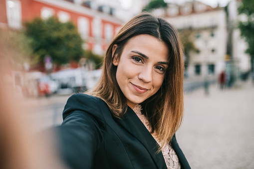 Point of view of cute businesswoman taking a self portrait in the city.