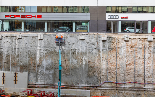 Monte Carlo, Monaco - October 14, 2020: A deep foundation excavation for the  L’îlot Pasteur project has been dug next to Porsche and Audi car showrooms. Workers are using a platform to access the retaining wall.