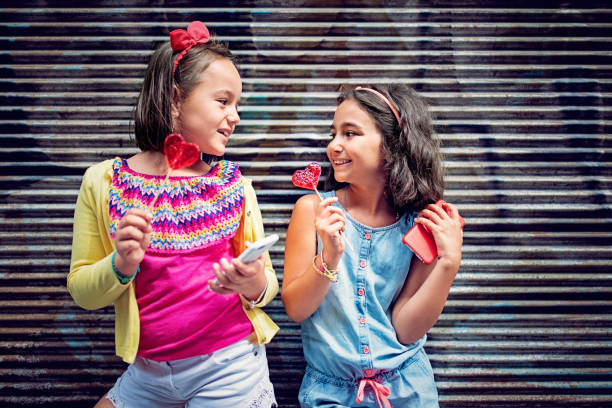 istock Girlfriends are having fun and eating heart shape lollipops 1299801729