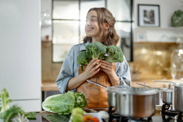 istock Woman with fresh broccoli on the kitchen 1299801948