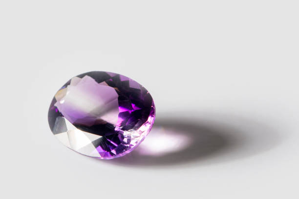 istock Large polished amethyst gemstone close-up on white background 1299802172