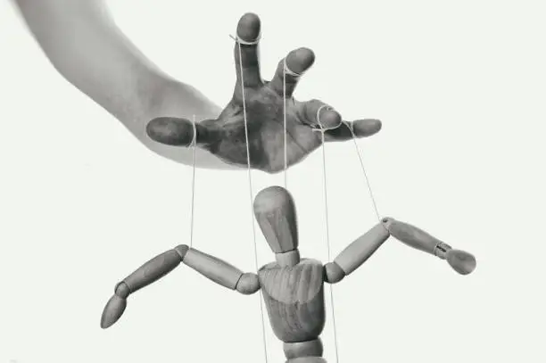 Concept of control. Marionette in human hand. Close-up. Black and white.