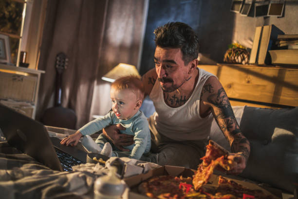 jeune père avec le corps couvert dans des tatouages se trouvant avec son fils de chéri sur le bâti dans la chambre à coucher - mature adult home interior chair contemporary photos et images de collection