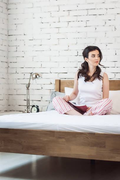 istock Friendly young woman with the book on the bed 1299805019