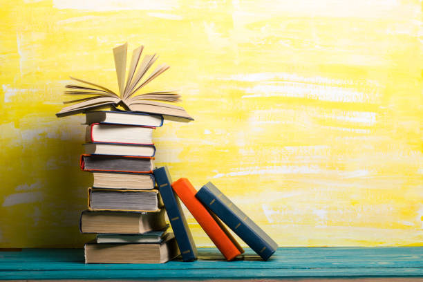 istock Books on bookshelf in Library. Back to School education concept on colored abstract yellow background. Open hardback book stack in a raw on wooden desk table. 1299805145