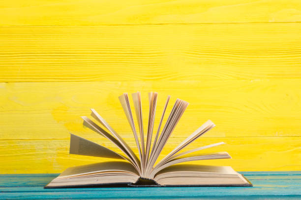 istock Books on bookshelf in Library. Back to School education concept on colored abstract yellow background. Open hardback book stack in a raw on wooden desk table. 1299805250