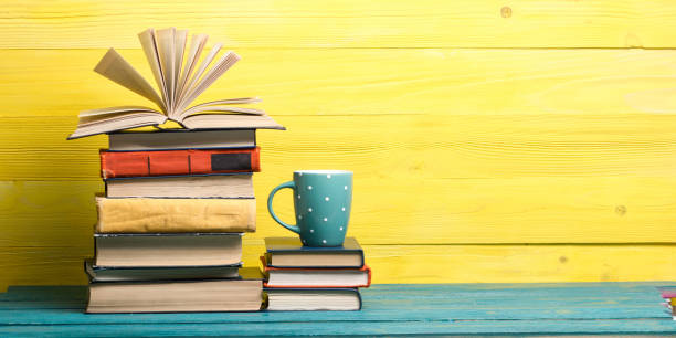 istock Books on bookshelf in Library. Back to School education concept on colored abstract yellow background. Open hardback book stack in a raw on wooden desk table. 1299805295
