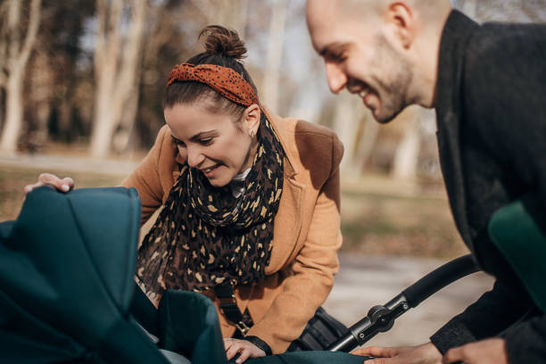istock Young parents with baby carriage in park 1299806742
