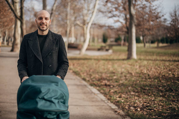 istock Young father with baby carriage in park 1299807182