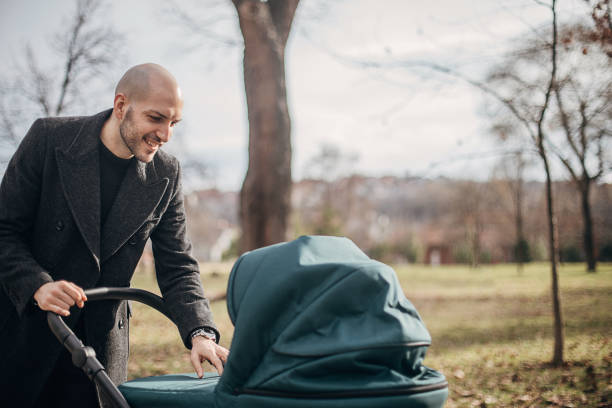 istock Young father with baby carriage in park 1299807198