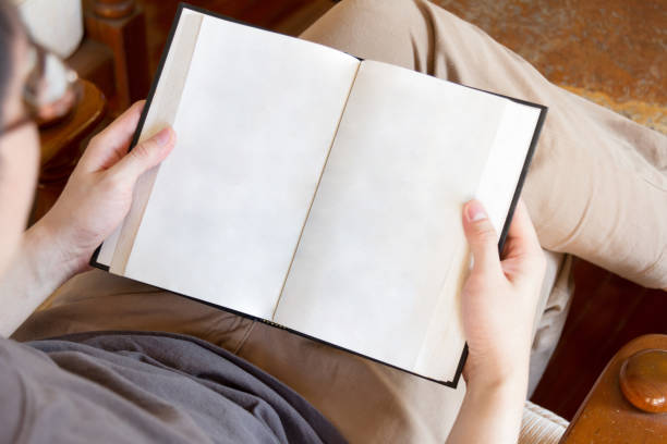 man sitting on sofa and reading book with blank pages stock photo