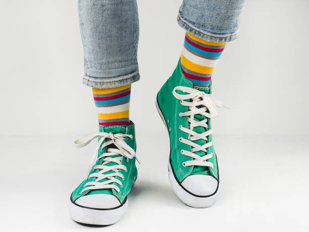 istock Green sneakers and funny socks on a white background 1299808494