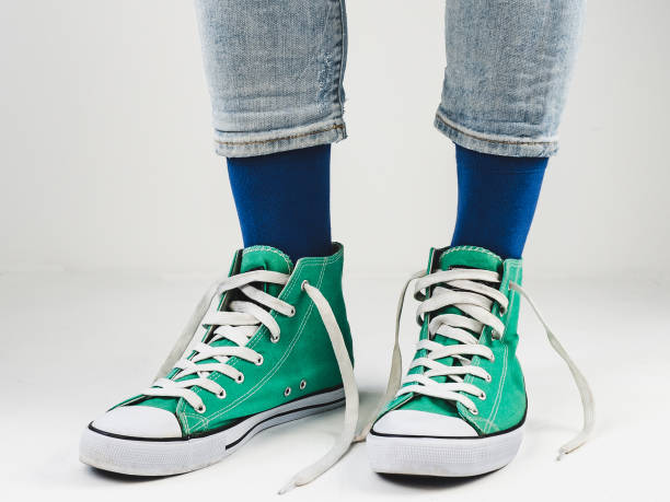istock Green sneakers and funny socks on a white background 1299809328