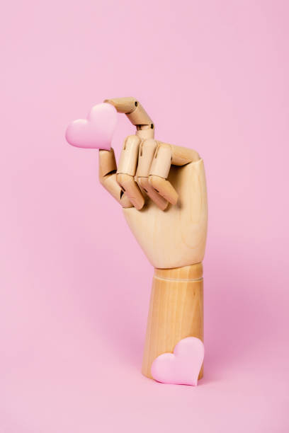 istock Human wooden hand model with heart on pastel pink. 1299809596