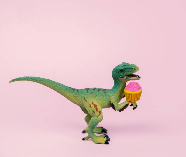 Cute green plastic dinosaur toy with cupcake decorated  pastel pink background. Cute green plastic dinosaur toy with cupcake decorated  pastel pink background. offbeat stock pictures, royalty-free photos & images