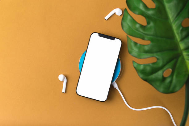 istock Modern smartphone with blank screen and bluetooth earphones on a brown background 1299809636