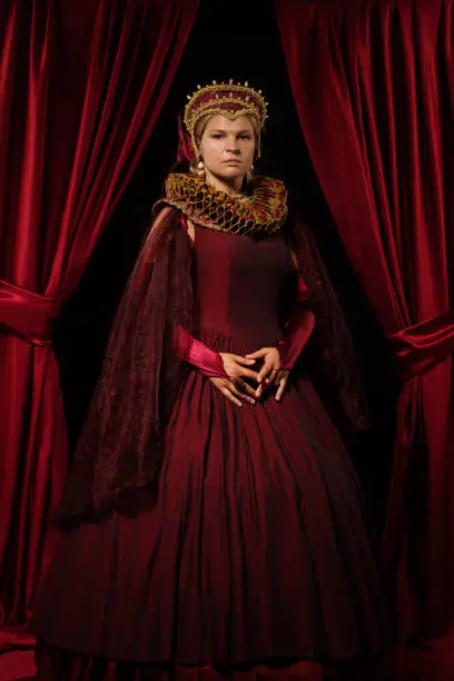 Beautiful historical blond Queen character wearing a period dress in a studio shot