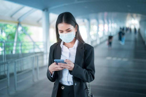 istock Young business woman with face mask  is standing on metro platform using smart. 1299811629