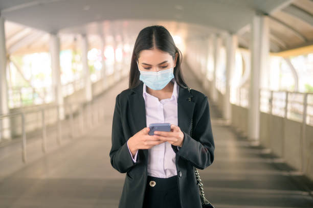 istock Young business woman with face mask  is standing on metro platform using smart. 1299811655
