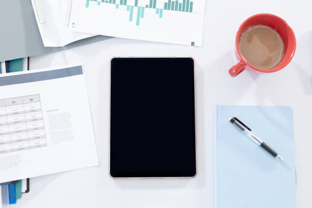 istock Office workstation desk with tablet computer paperwork and a cup of coffee 1299812772