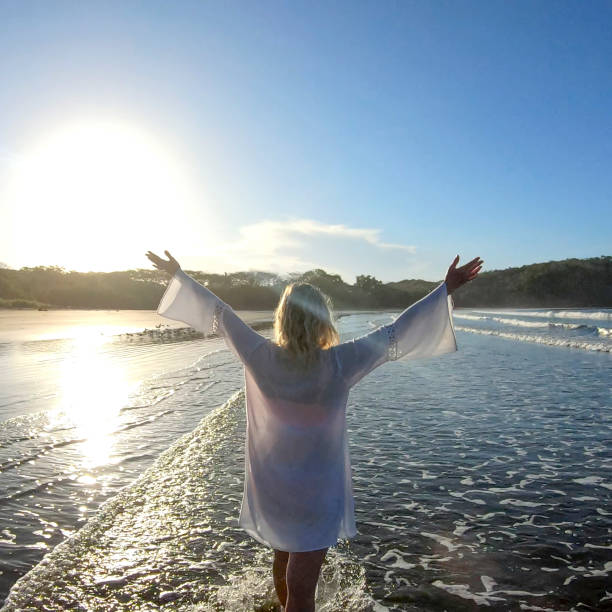 Woman walks down sandy beach in the morning