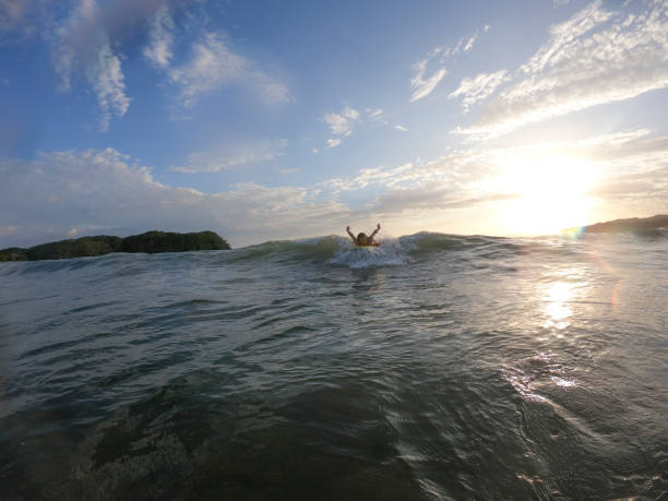 istock Young woman boogie boards to shore in the morning 1299817455