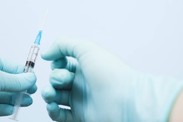 istock pump the vaccine with the syringe before the injection. on a blue background. copy space, close up 1299818558
