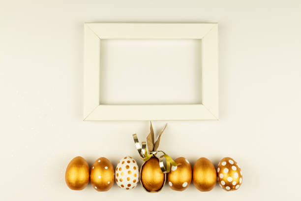 Cute still life of self painted mint green Easter eggs and a silver colored milk pot as a vase with a oilseed rape bouquet in front of a vintage picture frame. Creative color editing with added grain. Very soft and selective focus. Part of a series.