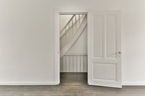 An open door in an empty room leading to a corridor with a staircase