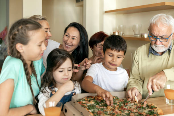 istock Multi-Generation Family Around Kitchen Island is Eating Tasty Pizza. 1299825078