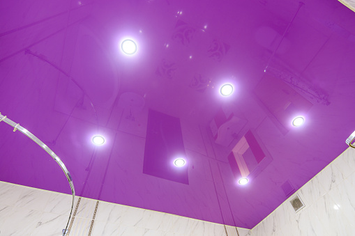 Stretch glossy ceiling of bright purple color in the bathroom