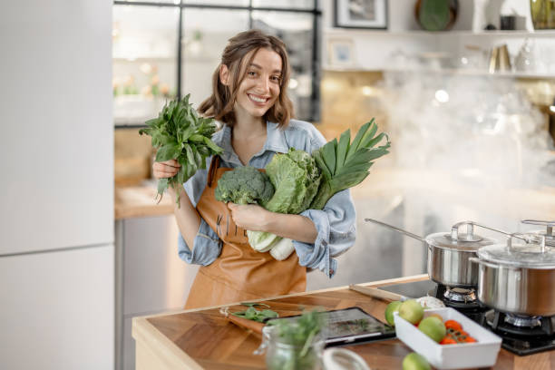 istock Woman with fresh green vegetables on the kitchen 1299828434