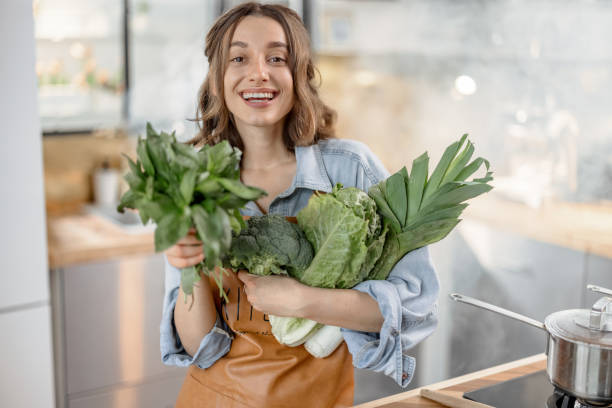 istock Woman with fresh green vegetables on the kitchen 1299828499