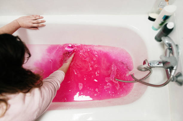 Putting a pink bath bomb in a bathtub