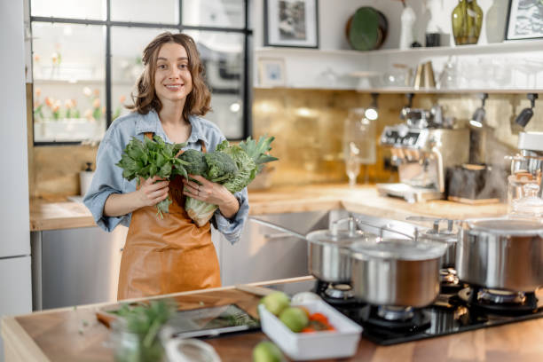 istock Woman with fresh green vegetables on the kitchen 1299830998