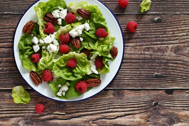 istock Fresh green salad with raspberry, goat cheese and caramelized pecans on rustic wooden table. 1299831023