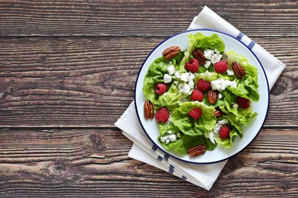 istock Fresh green salad with raspberry, goat cheese and caramelized pecans on rustic wooden table. 1299831077