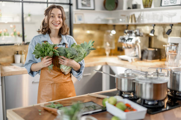 istock Woman with fresh green vegetables on the kitchen 1299831133