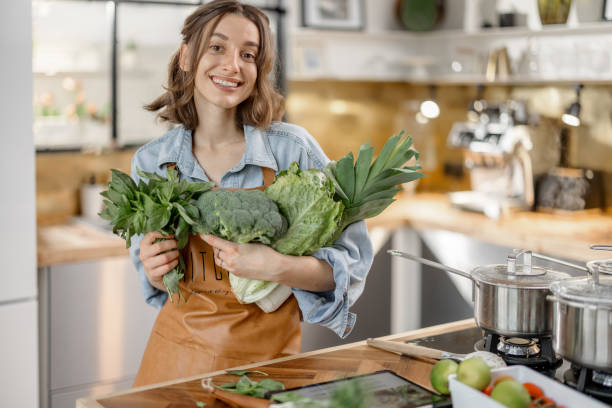 istock Woman with fresh green vegetables on the kitchen 1299831181
