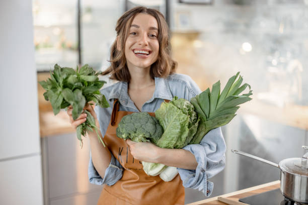 istock Woman with fresh green vegetables on the kitchen 1299831752