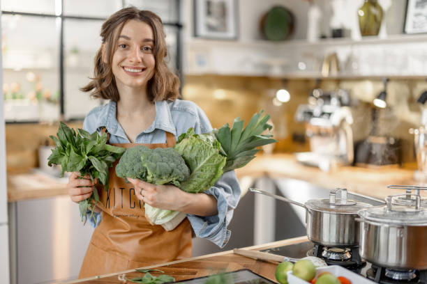 istock Woman with fresh green vegetables on the kitchen 1299831858