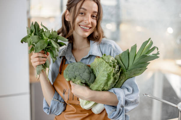 istock Woman with fresh green vegetables on the kitchen 1299831916