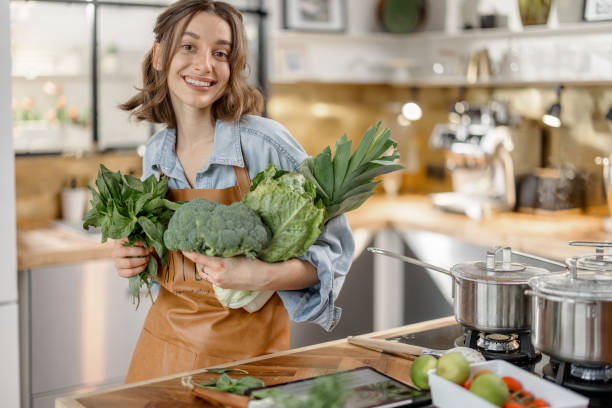 istock Woman with fresh green vegetables on the kitchen 1299831997