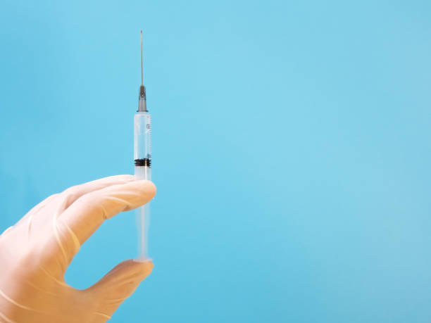 istock Syringe with vaccine in hand in medical gloves 1299832017