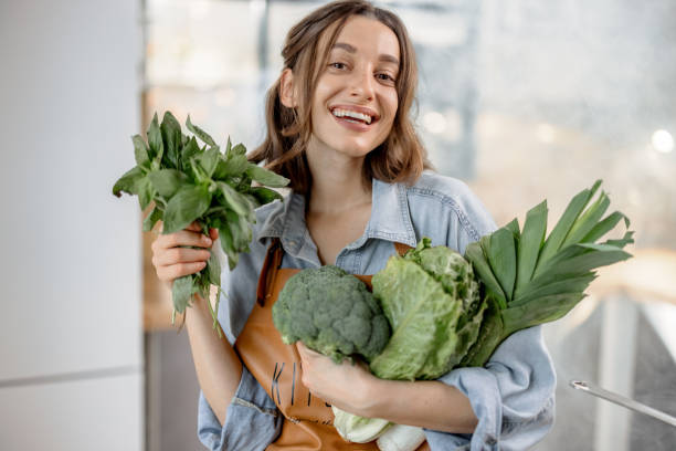 istock Woman with fresh green vegetables on the kitchen 1299832131