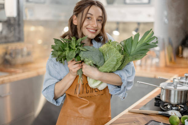 istock Woman with fresh green vegetables on the kitchen 1299833635
