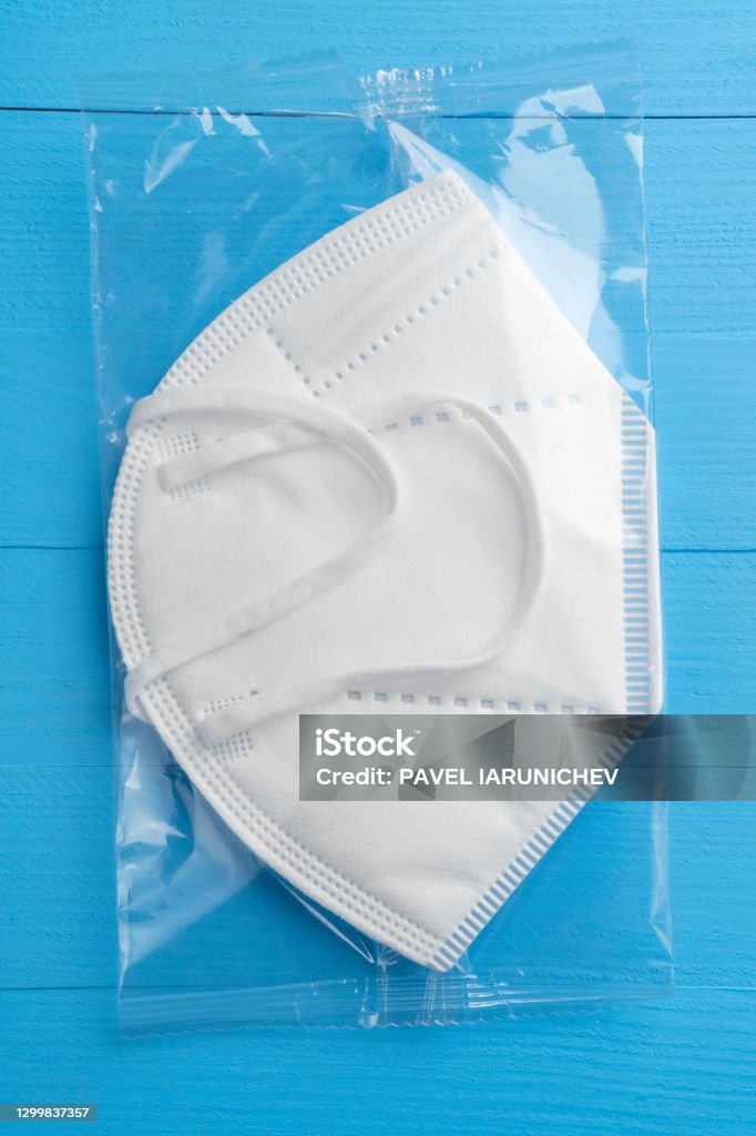 KN95 FPP2 medical respirator white mask KN95 FPP2 medical respirator white mask medical equipment on blue wooden background. Plastic pack Protective Face Mask Stock Photo