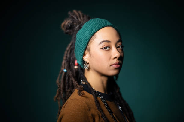 Studio portrait of young woman with blank expression Close-up portrait of young african american woman with blank expression against green background. Real people staring with locs - hairstyle and headband. person of color stock pictures, royalty-free photos & images