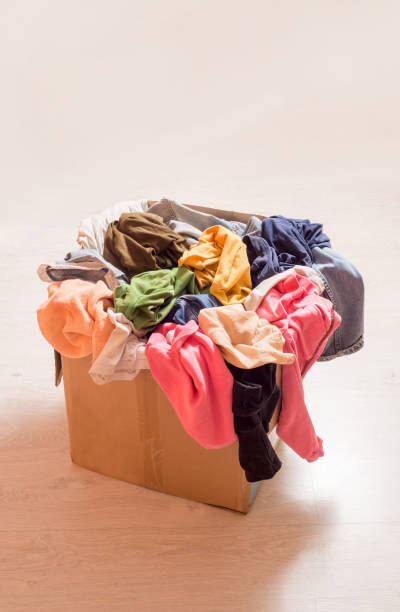 istock Pile of clothes in a large cardboard box. Sorting wardrobe and decluttering 1299841066